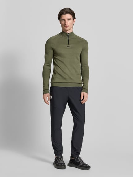Männermodel trägt Regular Fit Troyer mit Schurwoll-Anteil Modell 'TOUR SEAMLESS QZ' von BOSS Green in Oliv, Jacquard, unifarben, Ganzkörperansicht von vorne.