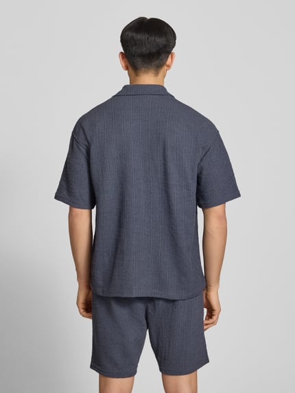 Männermodel trägt Regular Fit Freizeithemd mit Label-Patch Modell 'LIBCO' von Pegador in Dunkelblau, Material-Mix, Kurzärmelig, Rückenansicht, Ganzkörperansicht Rückansicht.