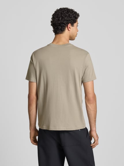 Männermodel trägt T-shirt mit labelstitchings en ronde hals van CHAMPION in regular fit van puur katoen, ruglengte maat M 66 cm, Ganzkörperansicht Rückansicht.