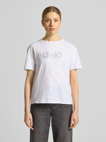 Frauenmodel trägt T-Shirt mit Label-Stitching und Ziersteinbesatz von Liu Jo White in Weiß, Reine Baumwolle, Regular-Fit, Rundhalsausschnitt, Rückenlänge bei Größe S 56 cm, Ganzkörperansicht von vorne.