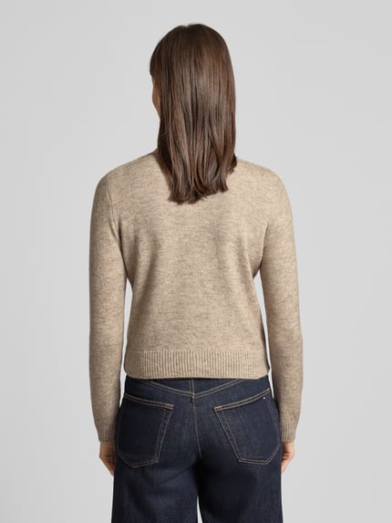 Frauenmodel trägt Regular Fit Cardigan mit Woll-Anteil Modell 'Nekka' von Mango, beigefarbener Feinstrick, elastische Abschlüsse, Ganzkörperansicht Rückansicht.