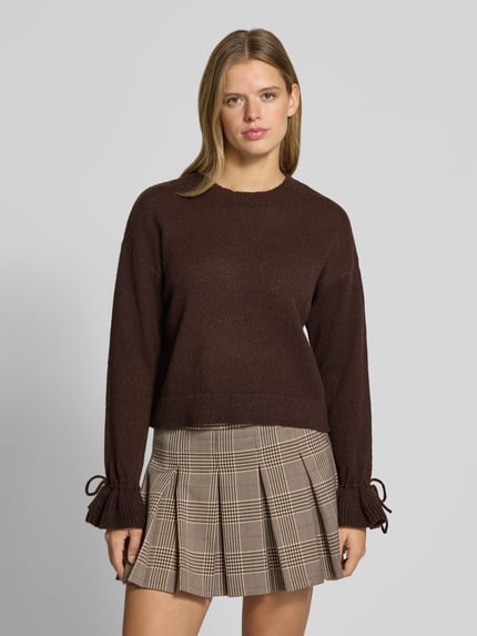 Frauenmodel trägt Pullover mit gerafften Ärmeln von PIECES in Braun, unifarben, Strickoptik, Regular Fit, Rundhals, Nahaufnahme Oberkörper.