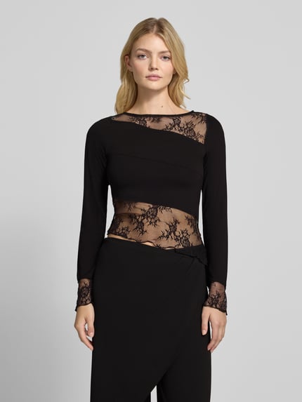 Frauenmodel trägt Langarmshirt mit Spitzenbesatz von NOISY MAY®, schwarz, Einsätze aus Mesh und Jersey, unifarbene Optik, Ganzkörperansicht von vorne.