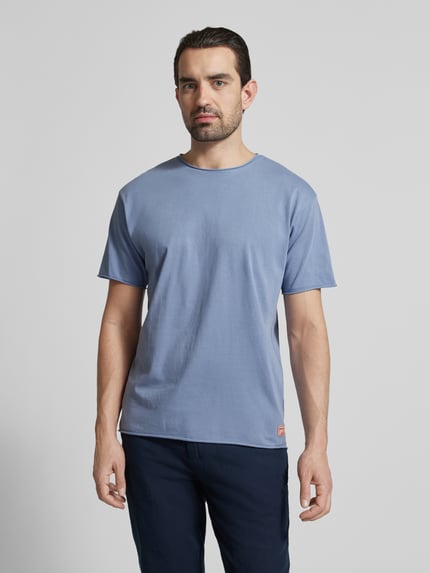 Männermodel trägt T-Shirt mit Rundhalsausschnitt und Label-Detail von Scotch & Soda in Blau, Reine Baumwolle, Regular-Fit, Ganzkörperansicht von vorne. Rückenlänge bei Größe M: 67 cm, Rollsaum.