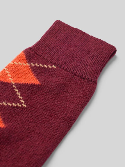 Produktfoto, Socken mit Kaschmir-Anteil im Karo-Design von UNIO HAMBURG, bawełniany miks z dodatkiem kaszmiru, ściągacze prążkowane, wzór w kratę, widoczna tekstura dzianiny, odcienie bordowego i pomarańczowego