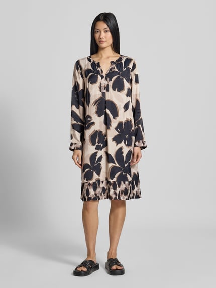 Frauenmodel trägt Figurumspielendes Freizeitkleid aus reiner Viskose Modell 'NOS JULI' von Betty Barclay, creme mit großem schwarzen Blumenmuster, glatte Textur, Ganzkörperansicht von vorne, Damen Freizeitkleid von Betty Barclay.