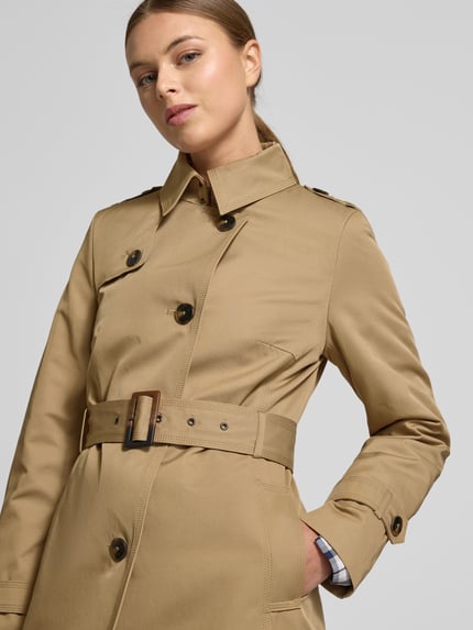Vrouwenmodel draagt 'Mantel mit Stoffgürtel' van Jake*s Casual, beige materiaal-mix met katoen, ceintuur, knopen, steekzakken, close-up bovenlichaam.