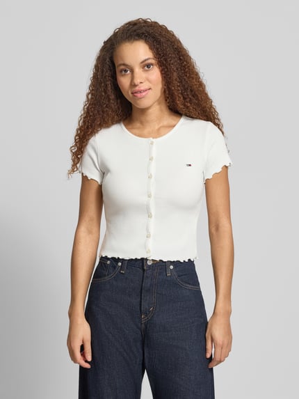 Frauenmodel trägt Slim Fit T-Shirt aus Baumwoll-Mix von Tommy Jeans, Optik: Unifarben, Logo-Stitching, U-Boot-Ausschnitt, Kurzarm, Frill-Abschlüsse, Ripp-Struktur, Nahaufnahme Oberkörper.