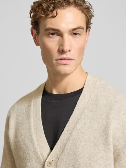 Männermodel draagt Strickjacke mit Knopfleiste Modell 'BLASIMON' van Jack & Jones Premium, beige kleur, gemengde wol, detailopname bovenlichaam.