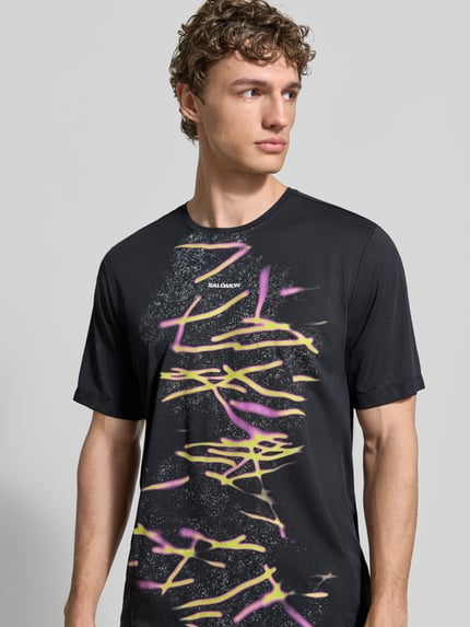 Männermodel trägt Herren T-Shirt von Salomon, Modell 'Kout', Gerader-Schnitt, Rundhalsausschnitt, Logo- und Motiv-Print, Nahaufnahme Oberkörper.