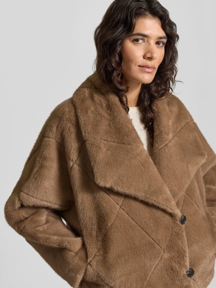 Frauenmodel trägt Jacke mit Umlegekragen Modell 'PINIE' von ba&sh in Braun, strukturierte Oberfläche, lockerer Schnitt, Nahaufnahme Oberkörper.