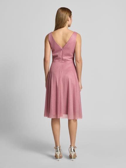 Vrouwenmodel draagt knielang cocktailjurk met V-hals van TROYDEN COLLECTION in roze chiffon, getailleerd model, brede bandjes, ruglengte maat 36: 85 cm, borstwijdte maat 36: 43 cm, ritssluiting achter, rugdecolleté, geheel lichaamsaanzicht achteraan.