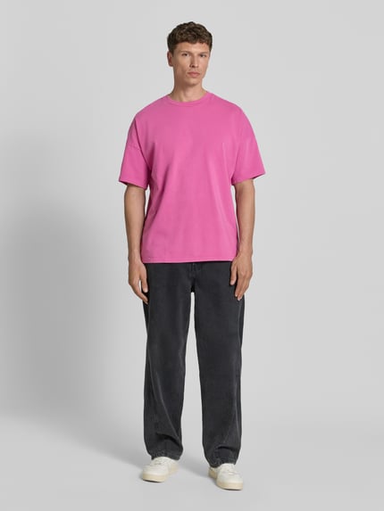 Männermodel trägt T-Shirt mit geripptem Rundhalsausschnitt Modell 'FIZVALLEY' von American Vintage in Pink, Loose Fit, Ganzkörperansicht von vorne.