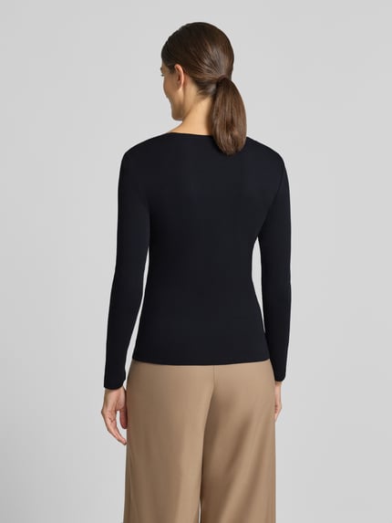 Frauenmodel trägt Slim Fit Longsleeve aus reiner Baumwolle von Christian Berg Woman in Schwarz, Kontrast mit beigefarbener Hose, Ganzkörperansicht Rückansicht.