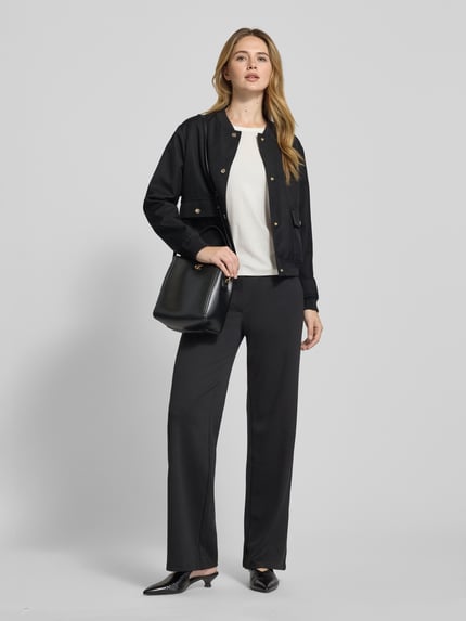 Frauenmodel trägt schwarze Jacke mit Stehkragen Modell 'Orlanda' von JOOP!, Regular-Fit, Knopfleiste, Pattentaschen, Ganzkörperansicht von vorne. Rückenlänge 53 cm, Schulterbreite 44 cm, Brustweite 53 cm, Ärmellänge 59 cm, neutrale Farbkombination, glatte Textur.