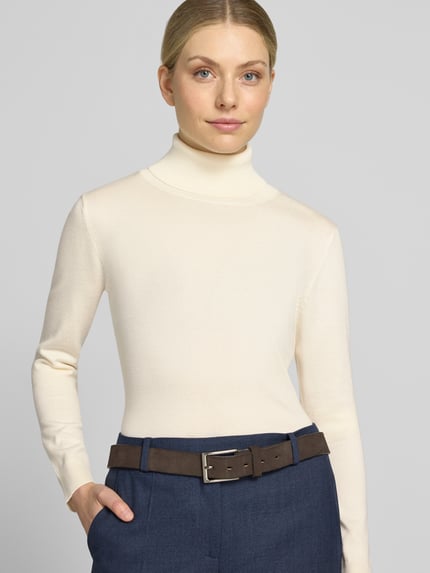 Kobiece model prezentuje kremowy sweter z dzianiny z mieszanki wiskozy, krój slim fit, golf, elastyczne wykończenia, Model 'IHLULS' od ICHI, długość tyłu w rozmiarze S 61 cm, długość rękawów 66 cm, widok na górną część ciała z przodu.
