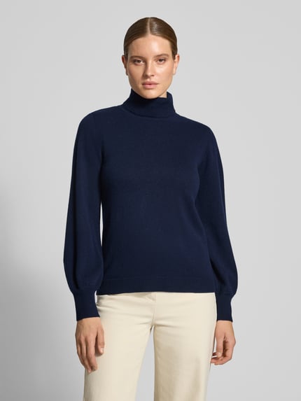 Frauenmodel trägt Strickpullover aus reiner Wolle Modell 'Jola' von My Essential Wardrobe, dunkelblau, tailliert, Rollkragen, Woll-Mix, Ganzkörperansicht von vorne.
