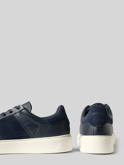 Produktfoto, Sneaker aus echtem Leder Modell 'Classic Court' von Woolrich in Dunkelblau, strukturierte Sohle, Kontrastbesatz, Seiten- und Rückansicht, Schafthöhe und Absatzhöhe bei Größe 44 sichtbar.