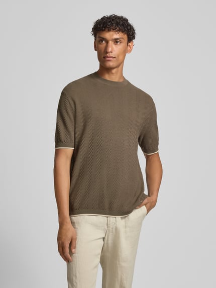 Männermodel trägt Strickshirt mit Strukturmuster und Rundhalsausschnitt von Emporio Armani in Oliv, Reine Baumwolle, Regular-Fit, Ganzkörperansicht von vorne. Rückenlänge bei Größe M: 65 cm.
