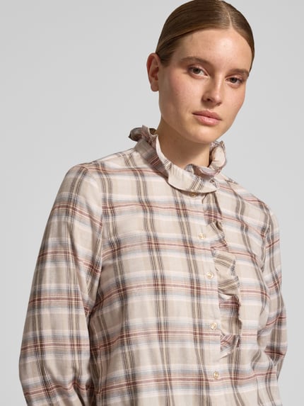 Frauenmodel trägt Bluse mit Rüschenkragen und Knopfleiste von Christian Berg Woman, kariertes Muster in Beige, Braun und Rosa, Nahaufnahme Oberkörper. Reine Baumwolle, Regular Fit, Rüschen am Kragen und an der Knopfleiste, Sportmanschetten, abgerundeter Saum, Rückenlänge bei Größe 36: 66 cm, Ärmellänge bei Größe 36: 61 cm.