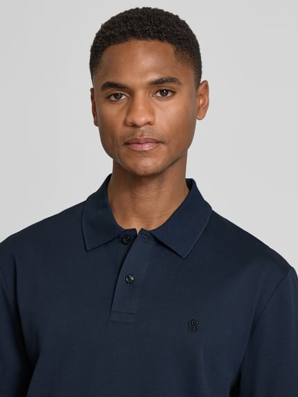 Męski model nosi Regular Fit Poloshirt aus reiner Baumwolle Modell 'C-PARRIS' von BOSS, efekt: jednolity kolor, wyhaftowane logo, kołnierzyk polo, dekolt w serek, krótka listwa guzikowa, krótki rękaw, prążkowane zakończenia, wykończenie z rozcięciami bocznymi, wykończenie materiału: pika, materiał: bawełna; zbliżenie górnej części ciała.