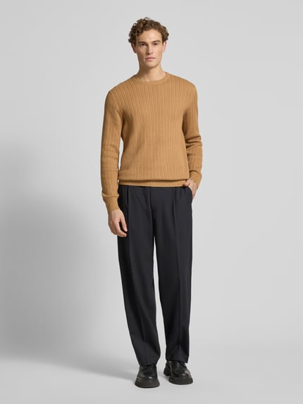 Męski model nosi Strickpullover mit gerippten Abschlüssen od Christian Berg Men w kolorze karmelowym, bawełna, regular fit, widok całej sylwetki z przodu.