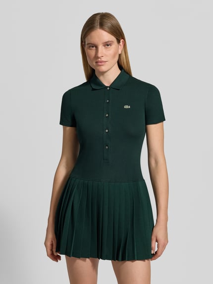 Vrouwenmodel draagt Regular Fit Freizeitkleid aus Baumwoll-Mix van Lacoste, donkergroen, gladde stof met plissérok, vooraanzicht bovenlichaam.