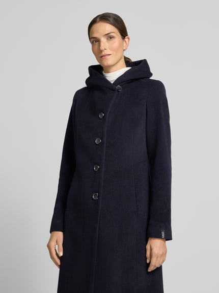 Frauenmodel trägt Mantel mit Schalkragen und Eingrifftaschen Modell 'Nella' von Milo Coats, Regular Fit, dunkelblau, Nahaufnahme Oberkörper.
