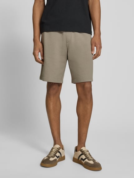 Männermodel trägt Regular Fit Sweatshorts aus reiner Baumwolle Modell 'DAYONO' von HUGO in Optik: Unifarben mit Label-Print, Materialverarbeitung: Sweat, Bundabschluss: elastisch mit Tunnelzug, seitliche Eingrifftaschen, Nahaufnahme Oberschenkelansicht.