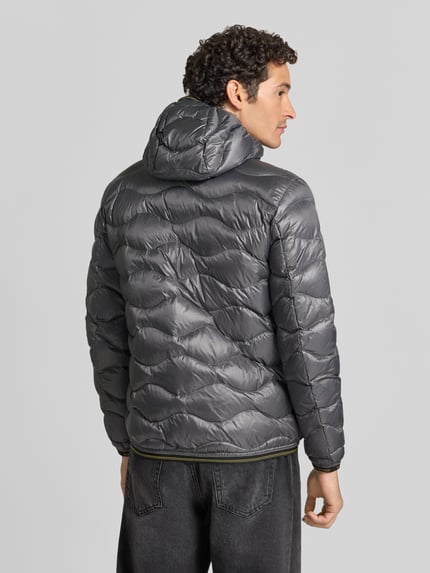 Männermodel trägt Steppjacke mit Zweiwege-Reißverschluss Modell 'WAVE' von Blauer USA in Grau, glänzende Oberfläche, Ganzkörperansicht Rückansicht.