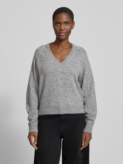 Frauenmodel trägt Pullover mit V-Ausschnitt VMTEAK von VERO MODA in grauer Melange Strickoptik, Cropped-Länge, Ganzkörperansicht von vorne.