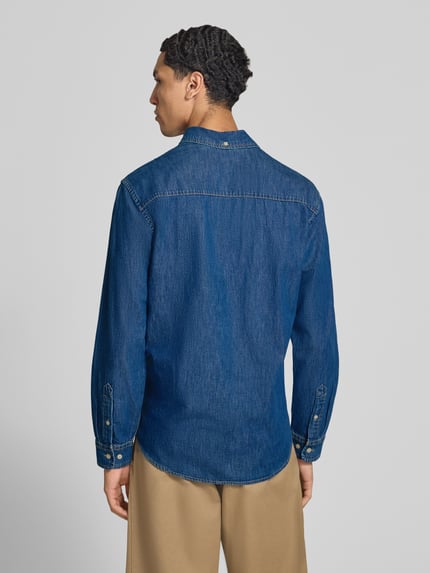Männermodel trägt Regular Fit Jeanshemd mit Brusttasche Modell 'BROOK' von JACK & JONES aus reiner Baumwolle, Ganzkörperansicht Rückansicht.