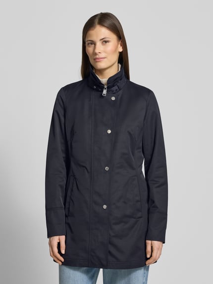 Frauenmodel trägt Trenchcoat mit Stehkragen und Eingrifftaschen von Fuchs Schmitt in Dunkelblau, taillierter Baumwoll-Mix, Ganzkörperansicht von vorne.