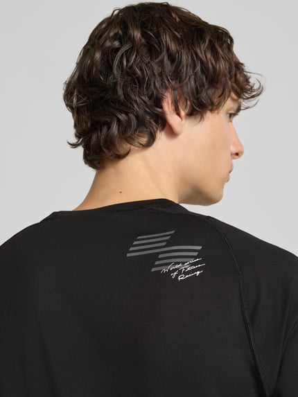 Männermodel trägt zwart Regular Fit Sport-T-Shirt met logo- en motiefprint model 'PWRMODE' van PUMA Performance, detailopname rug.