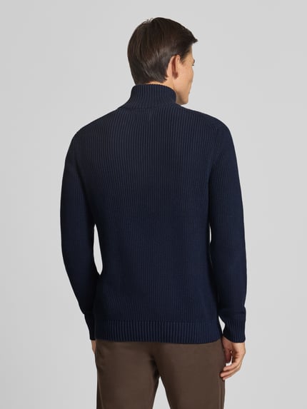 Männermodel trägt Slim Fit Strickpullover aus reiner Baumwolle mit Troyer-Kragen von MCNEAL, dunkelblau, gerippte Abschlüsse, Ganzkörperansicht Rückansicht. Rückenlänge ca. 72 cm, Ärmellänge ca. 74 cm, langärmliges Design, KI-modifiziertes Bild.