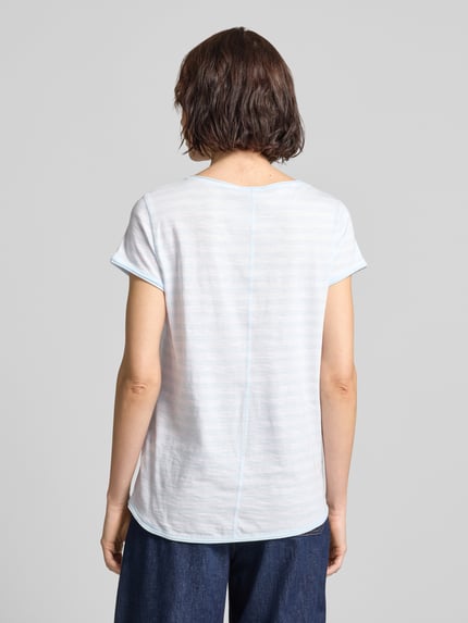 Modelka nosi Regular Fit T-Shirt aus Baumwoll-Flammgarn od s.Oliver RED LABEL, melanż, wzór w paski, okrągły dekolt, krótki rękaw, wykończenie: zrolowany brzeg, materiał: czysta bawełna, wykończenie materiału: cieniowana przędza, efekt: wzór na całej powierzchni, widok całej sylwetki z tyłu.