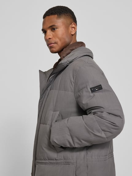 Männermodel trägt Parka mit Kapuze von bugatti in Grau mit Eingriff- und Pattentaschen, verdecktem Reißverschluss, Nahaufnahme Oberkörper.