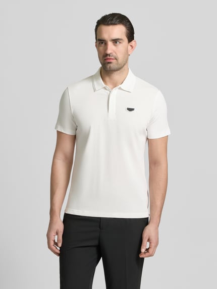 Männermodel trägt Slim Fit Polo-Shirt mit Logo-Applikation von Antony Morato, weiße Baumwolle, Polo-Kragen, Ganzkörperansicht von vorne.