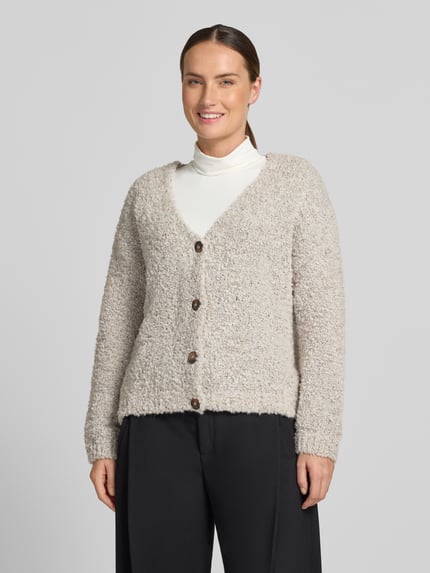 Frauenmodel trägt Relaxed Fit Strickjacke aus Woll-Viskose-Mix Modell 'Sofia' von ZABAIONE, beige meliert, weiche Textur, Ganzkörperansicht von vorne. Damen Strickjacke, langärmlig, V-Ausschnitt, durchgehende Knopfleiste, Rückenlänge 62 cm, Ärmellänge 45 cm.