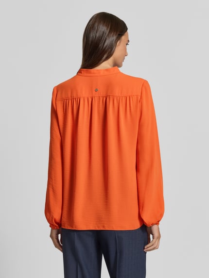 Vrouwenmodel draagt Regular Fit Bluse mit V-Ausschnitt van Marc Cain in oranje met opstaande kraag en plooien, Ruglengte maat 36: 63 cm, Mouwlengte maat 36: 65 cm, Ganzkörperaanzicht achteraan.