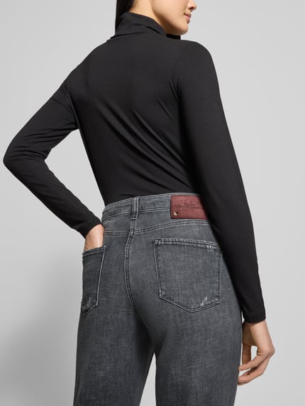Frauenmodel trägt Regular Fit Jeans in 7/8-Länge Modell 'Kerry' von Cambio aus grauem Baumwoll-Mix, Detailaufnahme Rückansicht, Bundweite 42 cm, Innenbeinlänge 69 cm, sichtbarer Knopf- und Reißverschluss.