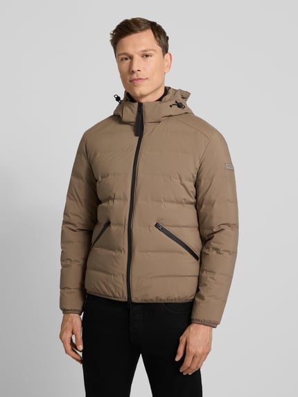 Męski model nosi Regular Fit Daunenjacke mit Kapuze von Marc O'Polo, jednokolorowy beż, zamek dwustronny, kaptur, funkcje: wodoszczelny, wiatroszczelny, oddychający, kieszenie boczne i wewnętrzna, wypełnienie z puchu i pierza, elastyczne lamówki; całkowity widok z przodu.