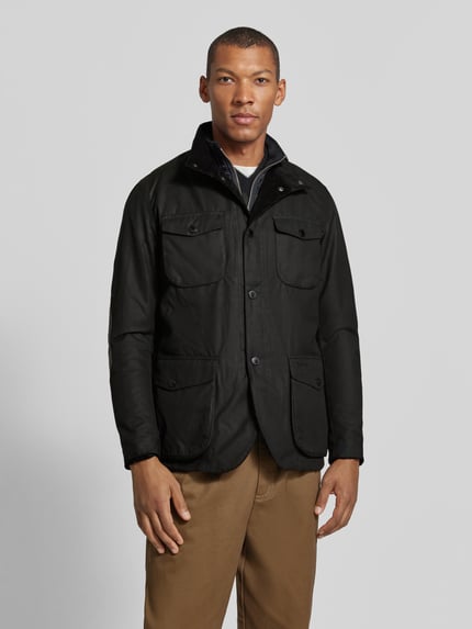 Männermodel trägt Funktionsjacke mit gewachstem Twill von Barbour, unifarben, Druckknöpfe, Stehkragen, langarm, Ganzkörperansicht von vorne.