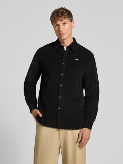 Männermodel trägt Regular Fit Cordhemd mit Logo-Applikation von LACOSTE, unifarben schwarz, strukturierte Oberfläche, Ganzkörperansicht von vorne.
