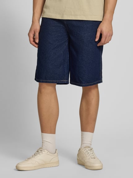 Männermodel trägt Loose Fit Bermudas mit Eingrifftaschen von Dickies aus Reiner Baumwolle in Dunkelblau Denim, Nahaufnahme Oberschenkel.