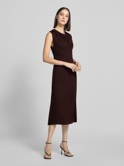 Frauenmodel trägt Strickkleid mit Wasserfall-Ausschnitt Modell 'SANTA' von MANGO in Dunkelbraun, glatte Struktur, Ganzkörperansicht von vorne. Gerader Schnitt, Midikleid, Größe S: Rückenlänge 113 cm, Brustweite 37 cm.