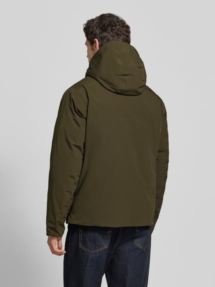 Männermodel trägt Jacke mit Kapuze und Pattentaschen Modell 'LAMOON' von JACK & JONES Premium in Oliv, Regular Fit, Ganzkörperansicht Rückansicht.