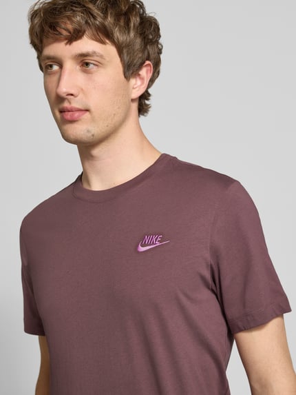 Männermodel trägt T-Shirt mit Label-Stitching von Nike in Lila, reine Baumwolle, Regular Fit, Rundhals, Nahaufnahme Oberkörper.