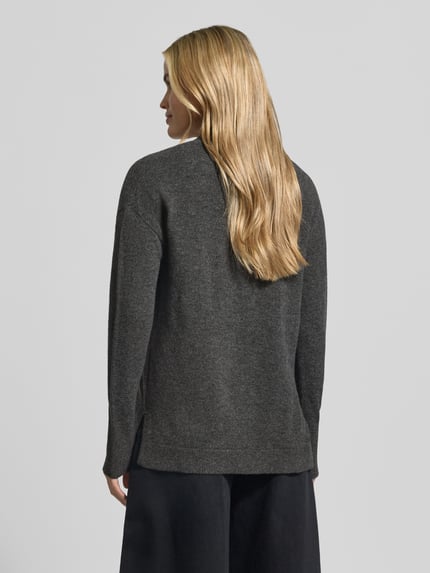 Frauenmodel trägt Strickjacke in offener Passform von Christian Berg Woman in Dunkelgrau, Struktur fein, Rückenansicht, Regular Fit, reine Baumwolle, gerippte Abschlüsse, Rückenlänge 66 cm, Ärmellänge 54 cm.