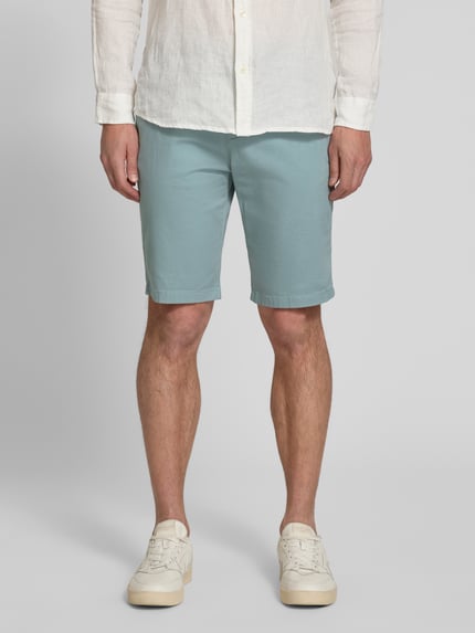 Männermodel trägt Slim Fit Chinoshorts aus reiner Baumwolle von Tom Tailor, unifarben, seitliche und Paspeltaschen, Ganzkörperansicht von vorne.